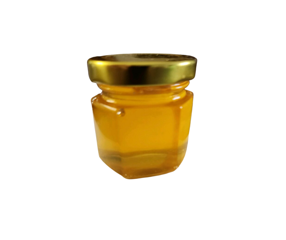 Mini honey jar with golden lid filled with natural raw honey.