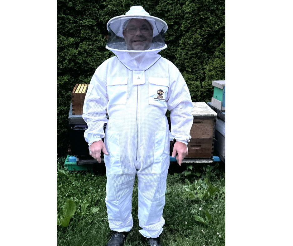 Beekeeper wearing ventilated beekeeping suit with detachable veil, standing near hives.